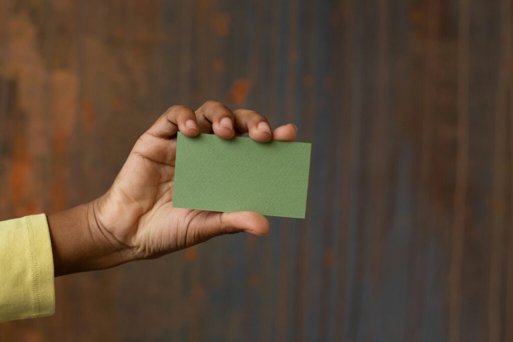 Unrecognizable African American person showing green mock up business card in hand
